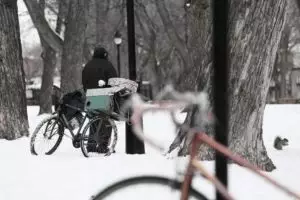 A man with a bicycle stands in the snow.